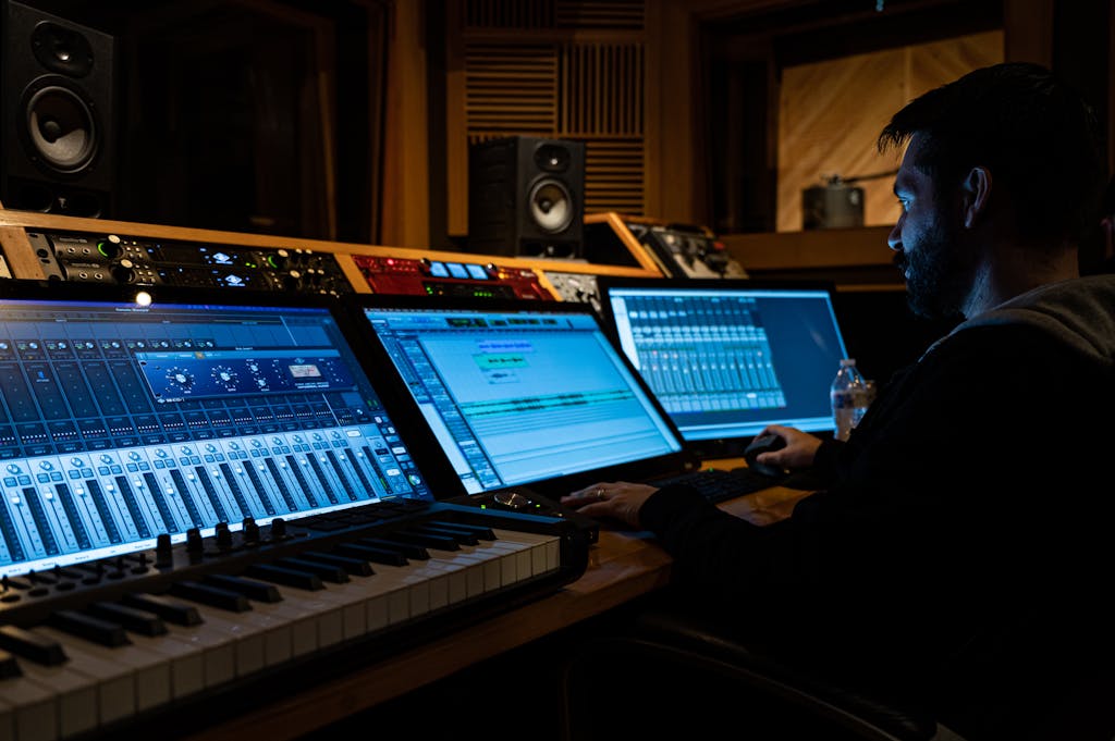 Side view of concentrated young male musician working on computer in studio while composing new song